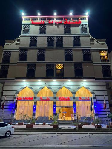 ein großes Gebäude mit einem beleuchteten Turm in der Nacht in der Unterkunft فندق ضيافة دلة in Dschidda