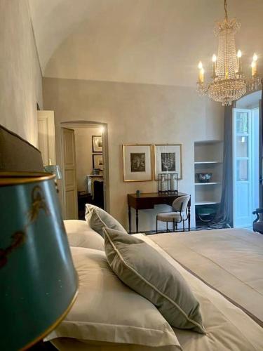 een slaapkamer met een groot bed met een kroonluchter bij Suite Vittorio Emanuele in Alba