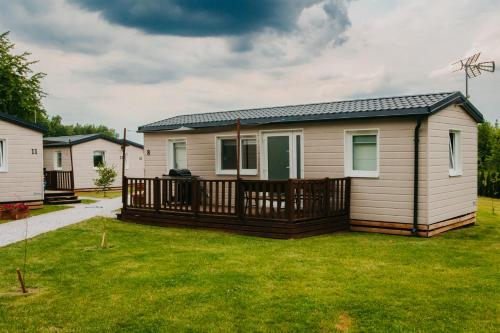 a mobile home with a deck and grass at LUXURY CAMP - 150 m od Suntago Park in Grabce-Towarzystwo