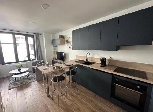 een keuken met zwarte kasten en een tafel en stoelen bij Appartement spacieux et tout confort in Le Pouliguen