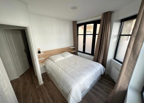 een slaapkamer met een wit bed en 2 ramen bij Appartement spacieux et tout confort in Le Pouliguen