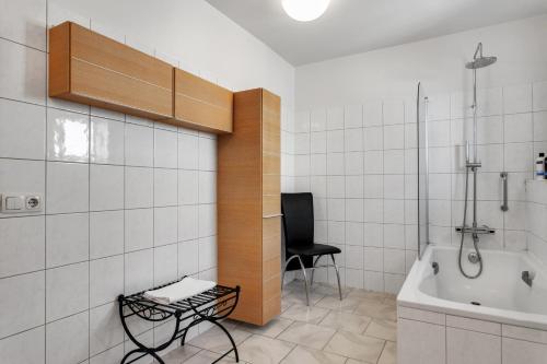 a bathroom with a tub and a chair in it at Baldursbrá Apartment Hverfisgata in Reykjavík