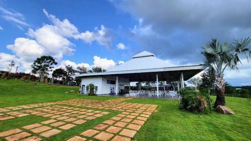 a white building with a palm tree in a field at Du Lịch Lâm Hà - Hồ Gia Trang Villas in Lam Ha