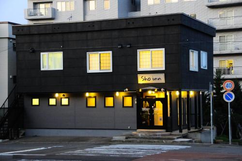 a black building with yellow lights on it at Sho inn MINIMAL HOTEL 小樽駅から無料送迎あり in Otaru