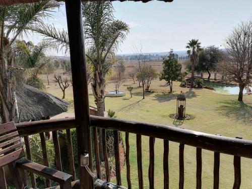 a balcony with a view of a park with palm trees at Kwena Maribane Lodge in Erasmus
