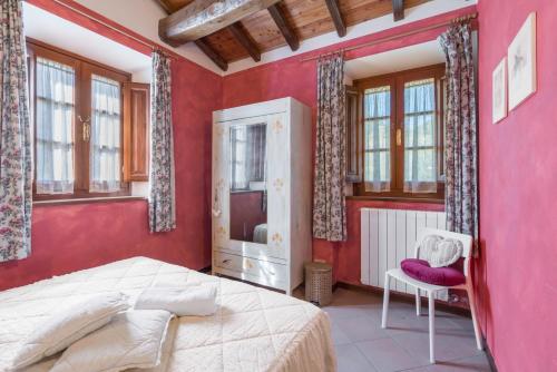 a bedroom with red walls and a bed and a chair at La Vecchia Fornace La Piastra Apartments shared pool- Abetone in Cutigliano