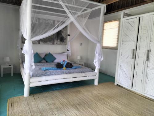 a bedroom with a white bed with a canopy at Tiki Boutique Hotel Lombok in Selong Belanak