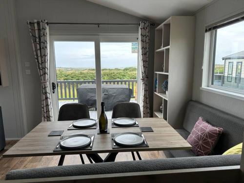 una mesa de comedor con una botella de vino. en Modern Lodge with Amazing Views en Newquay