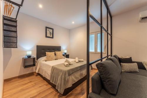 1 dormitorio con 1 cama y 1 sofá en Apartamentos Turísticos Jardín del Albarregas en Merida