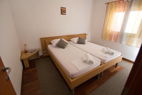 1 dormitorio con 1 cama con 2 almohadas y ventana en Apartments Kelić, en Trogir