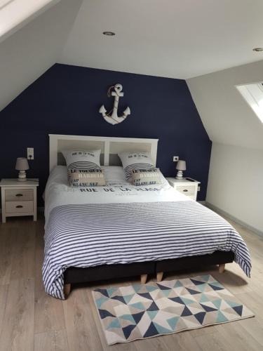 een slaapkamer met een groot bed met een blauwe muur bij Les nids de la Baie in Favières