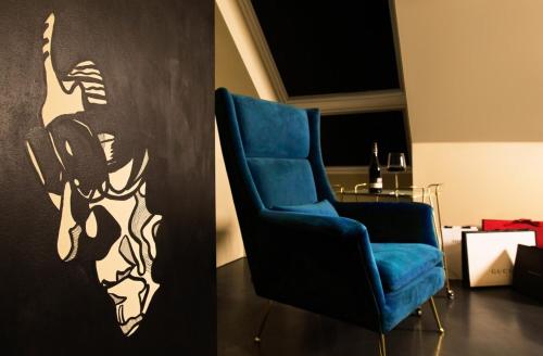 a room with a blue chair and a painting of a woman at Design-Hotel JAMS in Munich