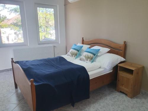 a bedroom with a bed with blue and white pillows at Tölgyeserdő Birtok Kaba Szállás és rendezvény in Kaba