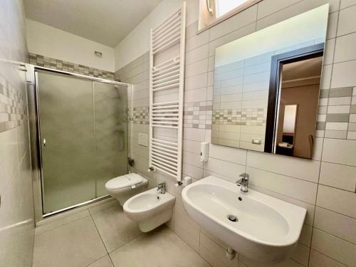 ein Badezimmer mit einem Waschbecken, einem WC und einem Spiegel in der Unterkunft Jogo Rooms in Matera