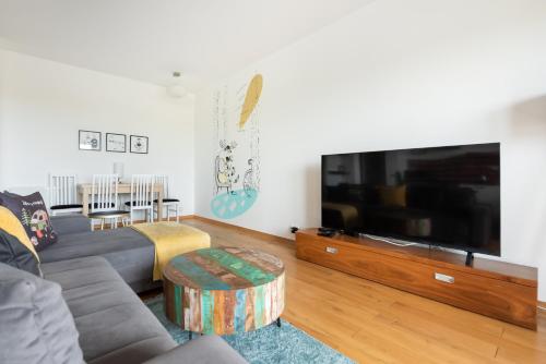 a living room with a couch and a large flat screen tv at Bemowo Kocjana 2-Bedroom Apartment in Warsaw