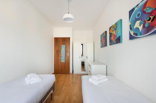 two beds in a room with white walls and wooden floors at Bemowo Kocjana 2-Bedroom Apartment in Warsaw