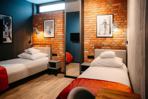 a bedroom with two beds and a brick wall at SLEEP WELL 1999 in Tychy