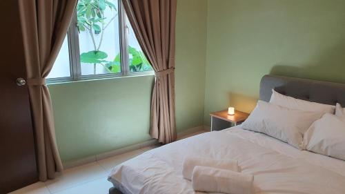 a bedroom with a white bed with a window at Duyong Damai Homestay by KOWBMAS in Melaka