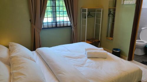 białe łóżko w pokoju z oknem w obiekcie Duyong Damai Homestay by KOWBMAS w Malakce