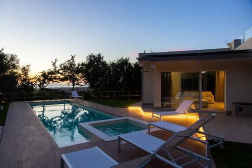 - une piscine avec 2 chaises et une maison dans l'établissement Modern villa with heated pool and sauna, à Marsala