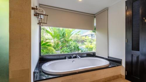 La salle de bains est pourvue d'une baignoire et d'une fenêtre. dans l'établissement Kejora 12 Beachfront 3 br Luxe Villa, à anur