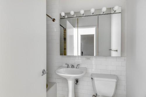 a bathroom with a sink and a toilet and a mirror at FiDi studio w gym doorman nr Freedom Tower NYC-1089 in New York