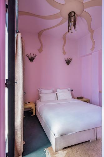 a bedroom with a white bed and a pink wall at Riad Goloboy in Marrakech