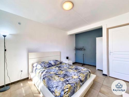 um quarto com uma cama com um edredão azul e branco em Zambaville - maison 2 chambres - Sainte-Anne em Saint-Benoît