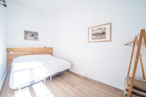 a bed in a room with white walls and wooden floors at La Vie est Belle - Entre ski et thermes in Ax-les-Thermes
