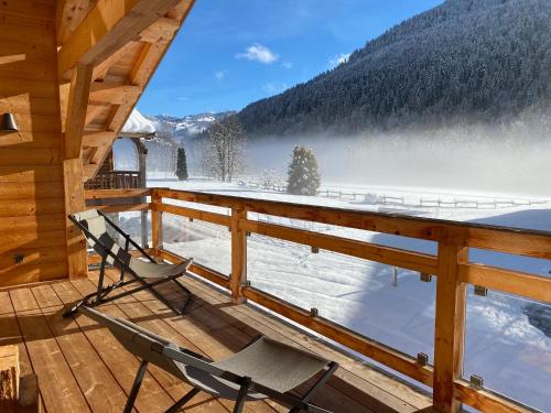 a deck with two chairs and a view of a snow covered mountain at Chalet Crêt Beni in La Chapelle-dʼAbondance