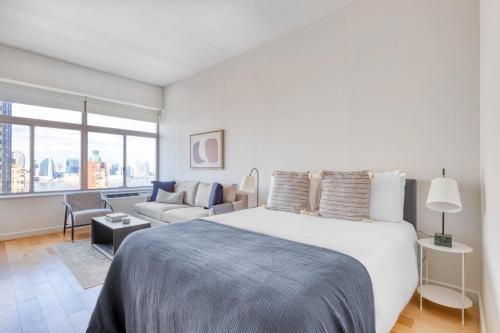 a white bedroom with a large bed and a couch at FiDi studio w gym doorman nr Freedom Tower NYC-1096 in New York