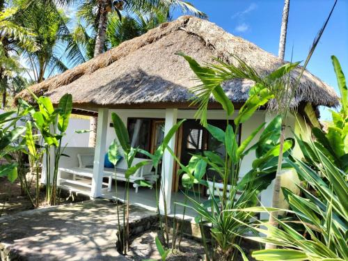 um chalé na praia com telhado de palha em Tiki Boutique Hotel Lombok em Selong Blanak