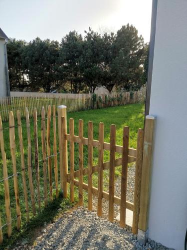 a wooden fence in front of a yard at Maison neuve à 2 pas des plus belles plages de Douarnenez - Classé Meublé de Tourisme 3 étoiles in Kerlaz