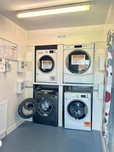 a laundry room with three washing machines and a washer and dryer at Red Deer Village Holiday Park - 3 Bedroom, Self-Catering Chalet in Steps