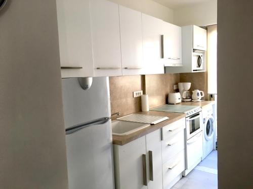 une cuisine avec des armoires blanches et un réfrigérateur blanc dans l'établissement Palais Lumière, à Cannes