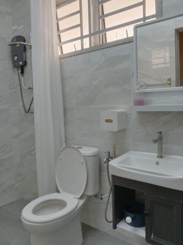 a white bathroom with a toilet and a sink at Sweet Homestay in Port Dickson
