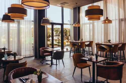 a restaurant with tables and chairs and large windows at ONOMO Airport Casablanca in Casablanca