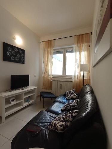 a living room with a black leather couch and a television at Maison G in LʼAquila