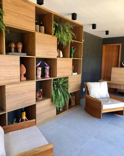 a room with wooden shelves with plants and a chair at Mani Milagres Studio - Gamboa Patacho in Pôrto de Pedras