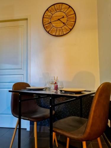 a table with chairs and a clock on the wall at Lyon Faubourg - Saint Priest in Saint-Priest
