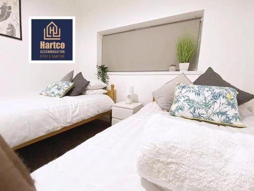 1 dormitorio con 2 camas con sábanas blancas y ventana en Botany House - Company & Family Stays en Bescot