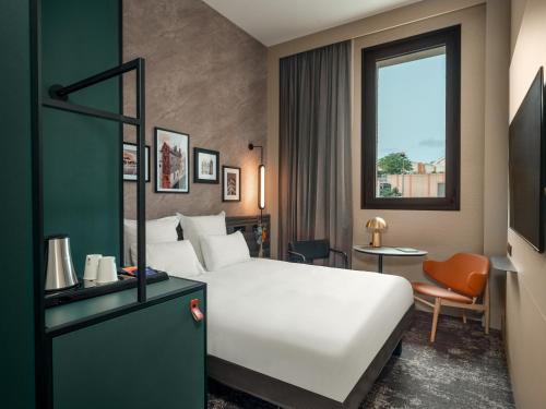 a hotel room with a white bed and a window at Novotel Orléans Centre Gare in Orléans