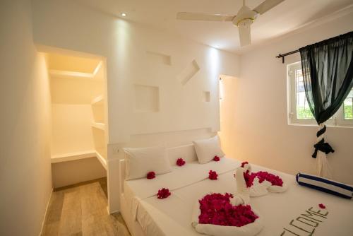 a bedroom with a white bed with red flowers on it at Villa Jiwe with Pool ZanzibarHouses in Kumba Urembo