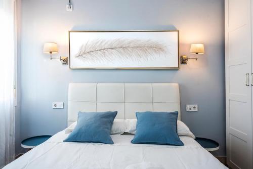 - une chambre avec un lit blanc et des oreillers bleus dans l'établissement Trendy Penthouse by the Bullring, à Séville