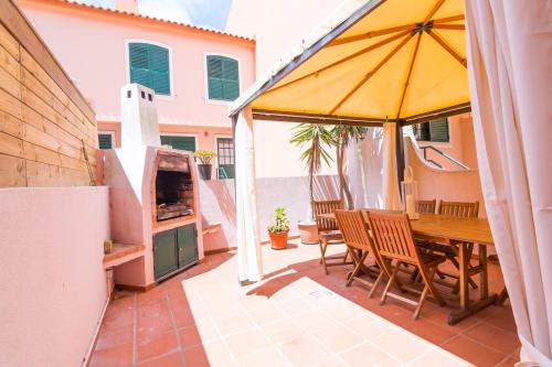a patio with a wooden table and an umbrella at Supertubos Beach Villa in Atouguia da Baleia