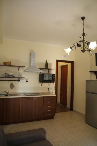 kuchnia z drewnianymi szafkami i żyrandolem w obiekcie Sole Nascente Apartment w mieście Giardini Naxos