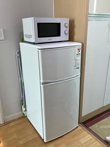 Un four micro-ondes est installé au-dessus d'un réfrigérateur. dans l'établissement Hongdae Station loft apartment, à Séoul