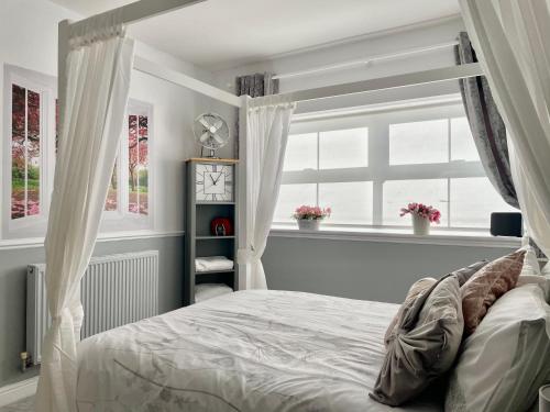 een slaapkamer met een bed met gordijnen en een raam bij Cosy Garden Flat, Private Roofed Hot Tub & Four Poster Bed in York