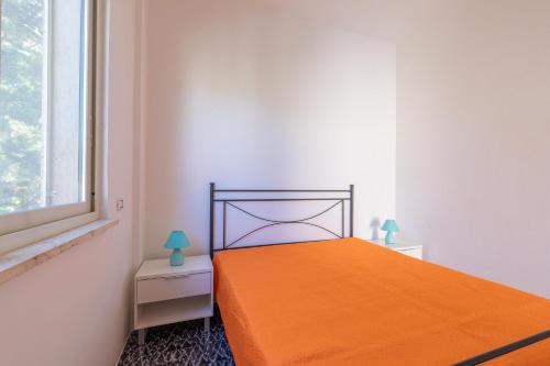 an orange bed in a white room with a window at Villetta Aloè in Torre Specchia Ruggeri