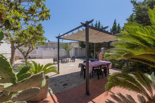 a table and chairs under an umbrella in a yard at Villetta Aloè in Torre Specchia Ruggeri